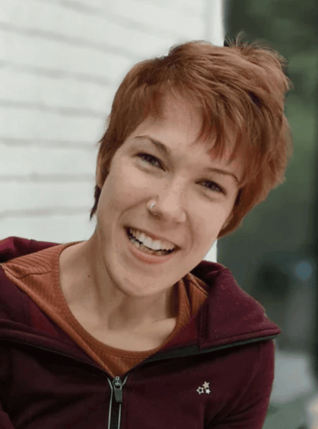 Portrait of Natascha Toman with short brown and slightly red hair and smiling.